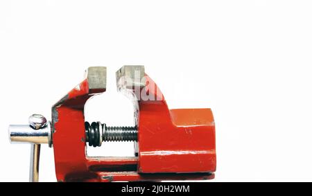 Close-up view of a red steel bench vise isolated on a white background Stock Photo