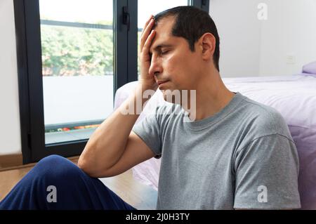 Cropped shot of a handsome young man sitting at the foot of his bed and feeling depressed while home alone Stock Photo