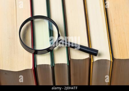 Magnifying glass over the stack of books at library Stock Photo