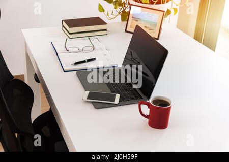 Cropped shot of technology and a laptop on a desk in an empty home office during the day with focus on the laptop screen Stock Photo