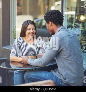 Theyre hitting it off on their first coffee date. Shot of a young couple on a coffee date at a sidewalk cafe. Stock Photo