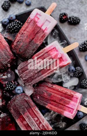Forrest fruit ice cream on stick. Homemade healthy vegan snack. Placed on plate with ice Stock Photo