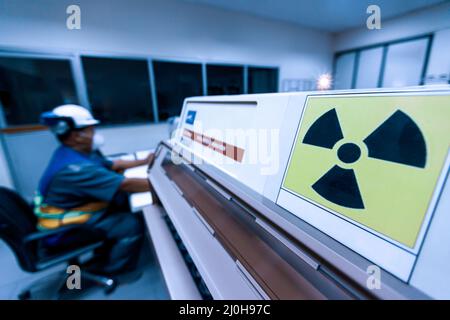 Male science researcher in protective uniform works in an x-ray laboratory, ionizing radiation hazard symbol in the foreground. Stock Photo
