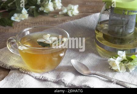 Tea with white flower petals and jasmine leaves Stock Photo