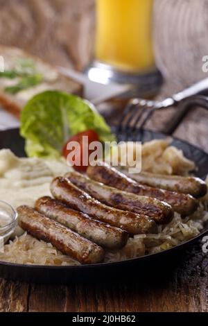 Grilled Nuremberger bratwurst with sauerkraut Stock Photo