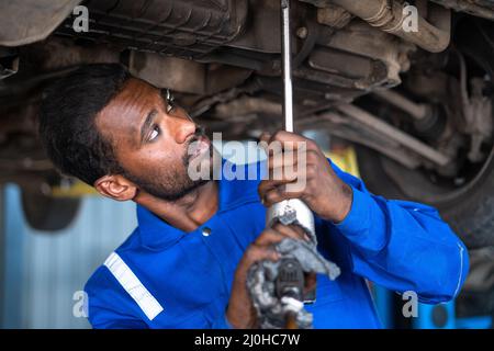 Car mechanic in uniform busy working using tools in under lifted vehicle at  garage - concept of hard working, expertise, professional occupation and  Stock Photo - Alamy