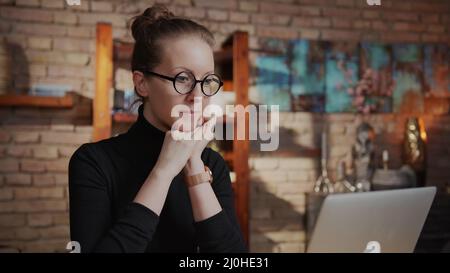 Smart woman in glasses working at home with laptop computer sitting at desk in home office. Stock Photo