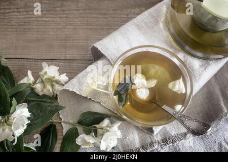 Tea with white flower petals and jasmine leaves Stock Photo