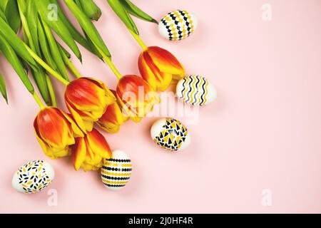 Golden, black and white Easter eggs with a geometric pattern with a tulips flowers on pink background. Copy space Stock Photo