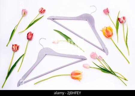 Clothes hangers with tulips on white background. Flat lay, top view Stock Photo