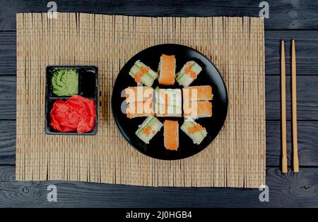 Sushi roll with salmon, on a black wooden background. Japanese kitchen . Sushi menu. Sushi set Philadelphia on a bamboo tablecloth. Stock Photo