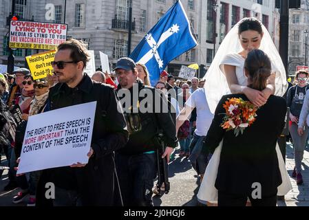 Westminster, London, UK. 19th Mar, 2022.A protest is taking place against vaccinating children for Covid 19, joined by anti-vaxxers. The march interrupted a wedding dress photoshoot with the Asian bride and white groom continuing regardless Stock Photo
