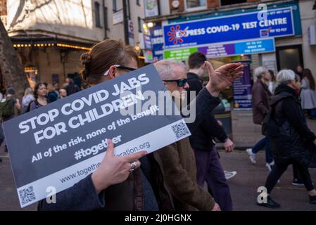 Westminster, London, UK. 19th Mar, 2022.A protest is taking place against vaccinating children for Covid 19, joined by anti-vaxxers. Protesters passing a Covid 19 test centre Stock Photo