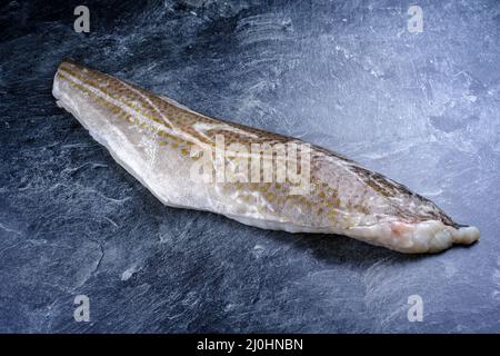 Raw Norwegian skrei cod fish filet with skin offered as close-up on black board with copy space Stock Photo