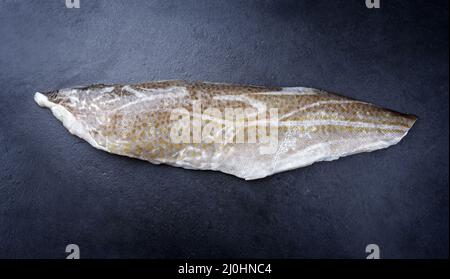 Raw Norwegian skrei cod fish filet with skin offered as top view on black board with copy space Stock Photo