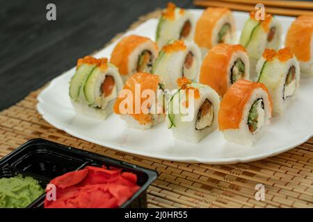 Sushi roll with salmon, on a black wooden background. Japanese kitchen . Sushi menu. Sushi set Philadelphia on a bamboo tablecloth. Stock Photo