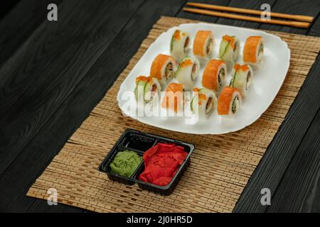 Sushi roll with salmon, on a black wooden background. Japanese kitchen . Sushi menu. Sushi set Philadelphia on a bamboo tablecloth. Stock Photo