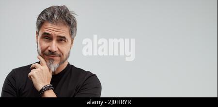 Portrait of happy older white man, beard gray hair, smiling. Gray background, wide banner, copy space. Stock Photo