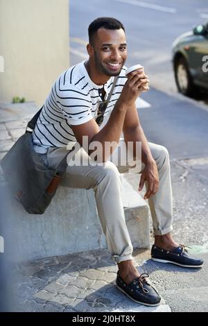 Enjoying coffee from his favorite spot. A handsome casually dressed african american businessman sitting in the city while drinking coffee. Stock Photo