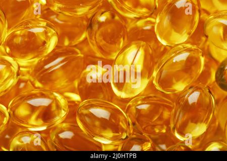 The texture of the capsules in the shell with liquid vitamin D3 in full screen. Gold capsules with a dietary supplement for joints teeth and bones. Stock Photo