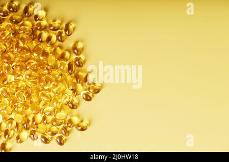 The texture of the capsules in the shell with liquid vitamin D3 in full screen. Gold capsules with a dietary supplement for joints teeth and bones. Stock Photo