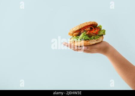 Female hand with tasty doner kebab in bun on color background Stock Photo