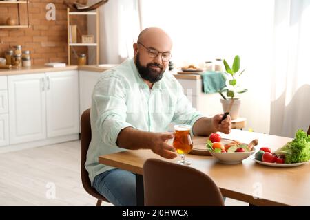 Man drinking beer while preparing lunch in kitchen Stock Photo