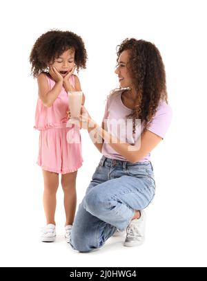 Surprised little African-American girl and her mother with glass of sweet cocoa on white background Stock Photo