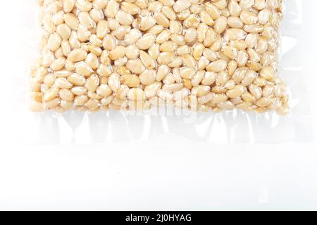 Pine nuts in a transparent vacuum package over a white background Stock Photo