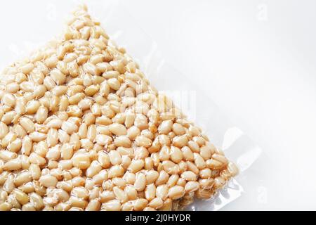 Pine nuts in a transparent vacuum package over a white background Stock Photo