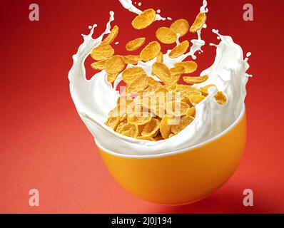 Corn flakes with milk splashes on red background Stock Photo