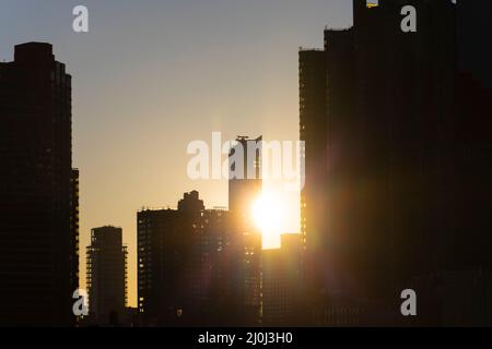 The sun sets among Midtown Manhattan skyscraper beyond the East River on November 2021 in New City. View from Franklin D. Roosevelt Four Freedoms Park Stock Photo