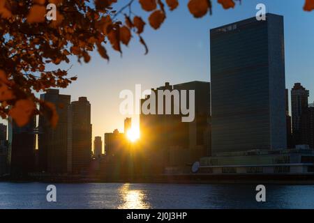 The sun sets among Midtown Manhattan skyscraper beyond the East River on November 2021 in New City. View from Franklin D. Roosevelt Four Freedoms Park Stock Photo