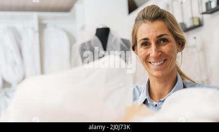 happy seamstress found tulle for a wedding dress. Tailor at work in her Studio Stock Photo