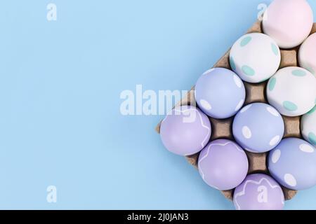 Box of pastel colored easter eggs on blue background with copy space Stock Photo