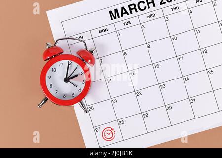 Concept for time change for Central European Summer Time on March 27th with red alarm clock and calendar sheet Stock Photo