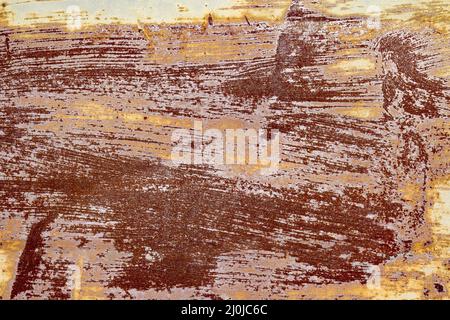 Red brown abstract background with pink and turquoise hues. A weathered, rust-eaten textured sheet of metal with traces of paint residue. Stock Photo