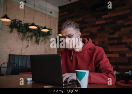 Portrait of happy male freelancer in optical eyewear for vision correction smiling at camera during break from web working online, cheerful hipster bl Stock Photo