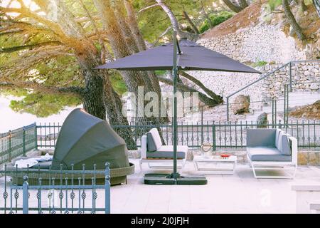 Beach umbrella and chaise for relax and comfort on balcony of hotel on sea coast. Happy summer vacations and  tourism concept. Stock Photo
