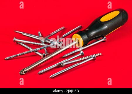 Screw driver and screws against a red background Stock Photo