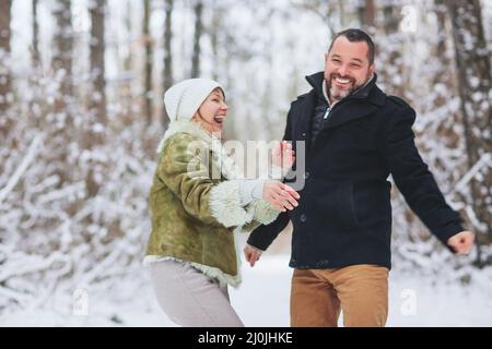 Lovely happy middle-aged family couple having fun outdoors in winter season together Stock Photo