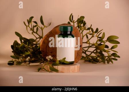 Misteltoe medicine in the bottle decorated with fresh twigs against beige background. Stock Photo