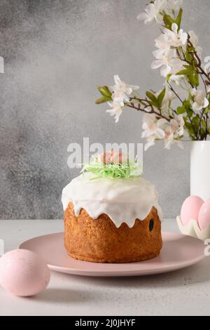 Easter cake, pink pastel eggs and spring blossom flowers on gray background. Vertical format. Holidays traditional food. Christian custom. Stock Photo