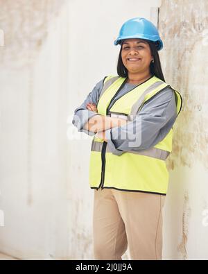 Running this site with confidence. Cropped portrait of an attractive young female construction worker standing with her arms folded on site. Stock Photo