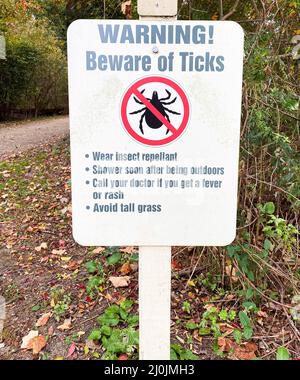 Beware of ticks sign posted at the top of a walking path in a local park. Stock Photo