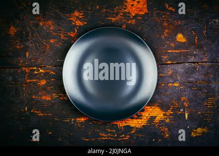 Empty black plate on a wooden vintage black grunge background top view Stock Photo