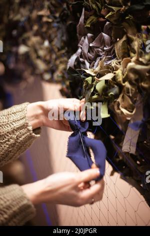 Women's hands weave a military camouflage net. Ukrainian women volunteers. Stock Photo