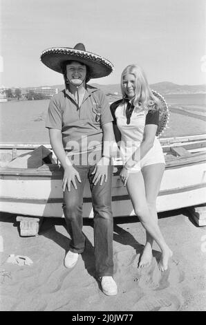 British darts player Eric Bristow poses with Maureen Flowers on the beach at Torremolinos Del Mar on the Costa Del Sol in Spain ahead of the Mediterranean Open Darts Championship. 31st January 1982. Stock Photo