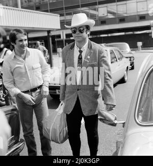 Dressed in a stetson hat, Elton John leaves Heathrow Airport for America. On the left is John Reid, Elton's manager. 10th August 1980.