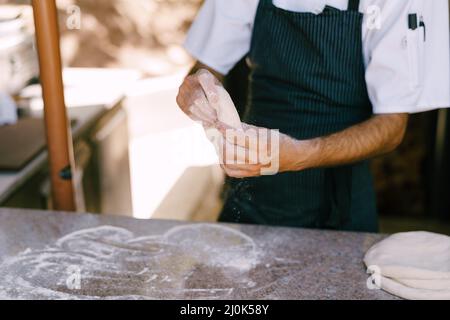 Chef's hands close-up. Prepares the dough for pizza, rolls out in round shapes with his hands. Stock Photo